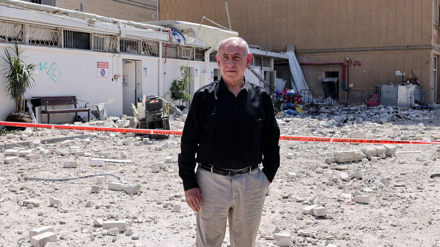 Israeli Prime Minister Benjamin Netanyahu stands amid debris outside the Soroka Hospital in the southern city of Beersheba, after it was hit by a missile fired from Iran on June 19, 2025. Israel's defence minister warned that Iran's supreme leader "can no longer be allowed to exist" after a hospital was hit in an Iranian missile strike on June 19, spiking tensions in the week-old war. (Photo by Marc Israel SELLEM / POOL / AFP) (Photo by MARC ISRAEL SELLEM/POOL/AFP via Getty Images)