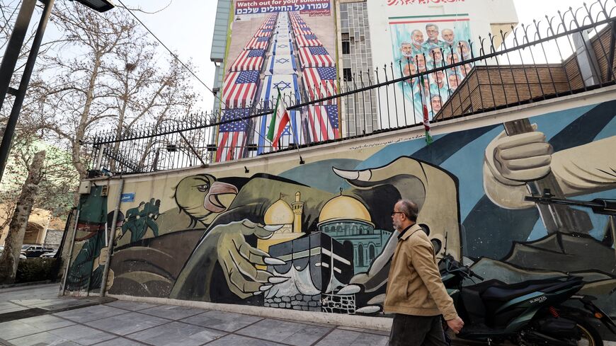 An Iranian man walks past an anti-US and anti-Israel banner hanging on a building in Palestine Square in Tehran on Jan. 27, 2026.