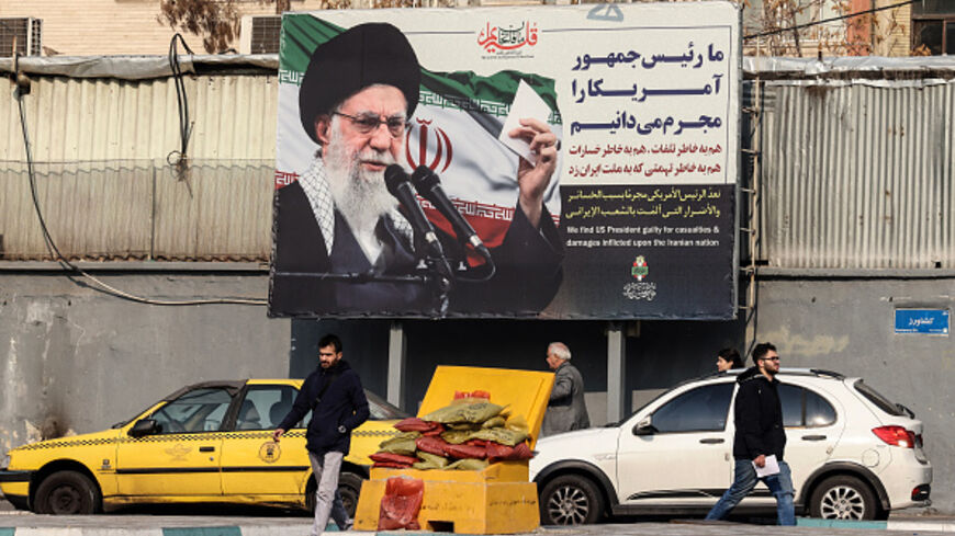 Iranians walk past a billboard showing Iranian supreme leader Ayatollah Ali Khamenei with anti-US rhetoric in Tehran on January 27, 2026. (ATTA KENARE / AFP via Getty Images)