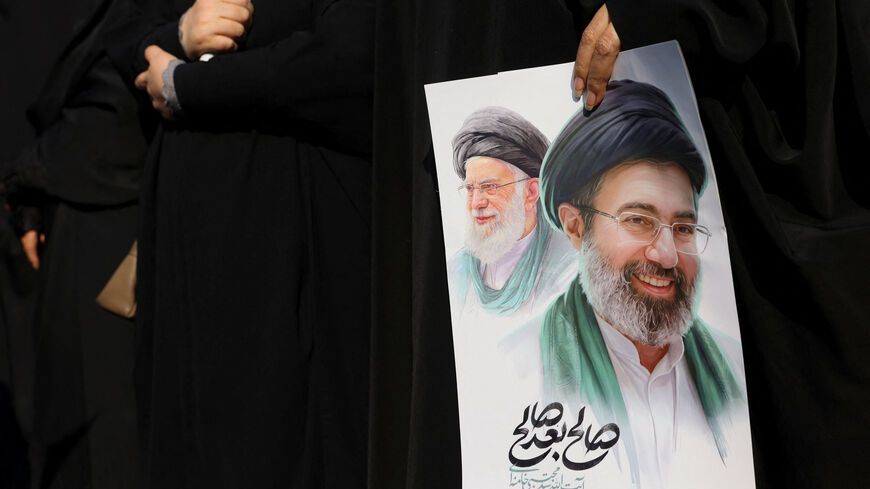 A woman holds an image of Iran's new supreme leader, Mojtaba Khamenei, alongside late Iranian Supreme Leader Ayatollah Ali Khamenei, during a funeral ceremony for the Iranian military commanders who were killed in strikes, amid the U.S.-Israeli conflict with Iran, in Tehran, Iran, March 11, 2026. Majid Asgaripour/WANA (West Asia News Agency) via REUTERS