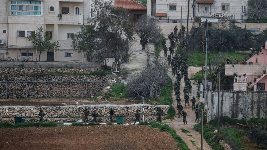 Israeli soldiers walk ahead of a Palestinian house demolition, in Dura, in the Israeli-occupied West Bank, March 14, 2026. REUTERS/Mussa Qawasma