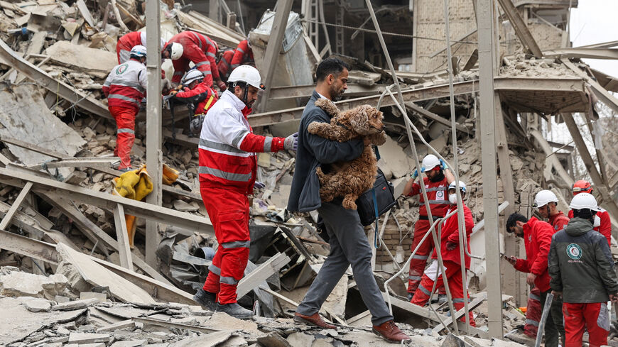 A man carries a dog as emergency personnel work at the site of a strike on a residential building, amid the U.S.-Israeli conflict with Iran, in Tehran, Iran, March 16, 2026. Majid Asgaripour/WANA (West Asia News Agency) via REUTERS