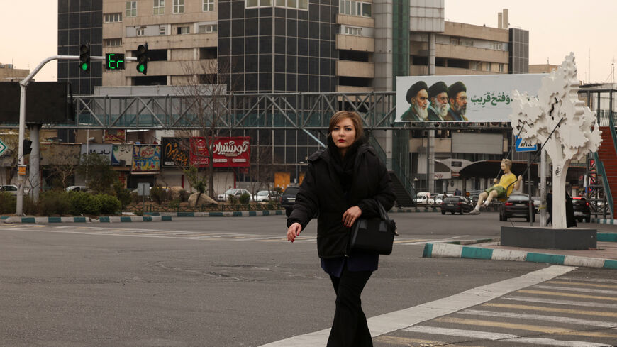 FILE PHOTO: A woman walks across the street, with a banner of all three leaders of Iran, late Ruhollah Khomeini, late Ayatollah Ali Khamenei, and Mojtaba Khamenei in the background, amid the US-Israeli conflict with Iran, in Tehran, Iran, March 15, 2026. REUTERS/Alaa Al-Marjani/File Photo