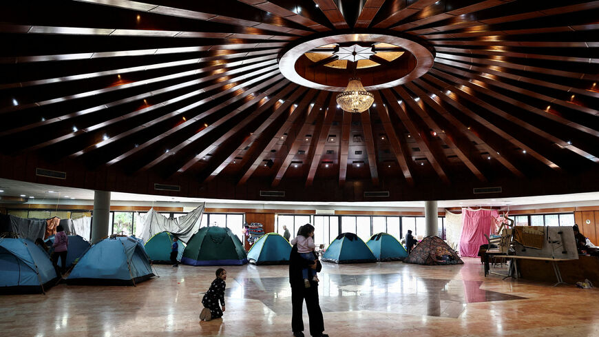 A woman holds a child in a school turned into a shelter for displaced families, amid escalating hostilities between Israel and Hezbollah, as the U.S.-Israeli conflict with Iran continues, in Dekwaneh, Lebanon. REUTERS/Yara Nardi