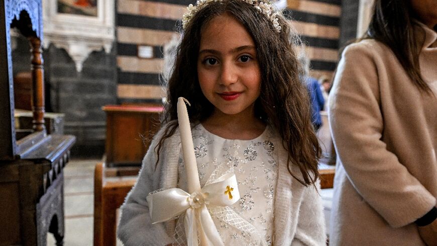 A young girl with an unlit candle during the Palm Sunday service at the Cathedral of Our Lady of Dormition in Damascus