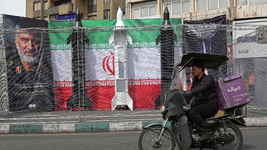 A motorist drives past mock Iranian missiles displayed in Tehran's Valiasr square on March 22