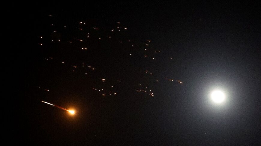 Rocket trails are seen next to the moon in the sky above Netanya