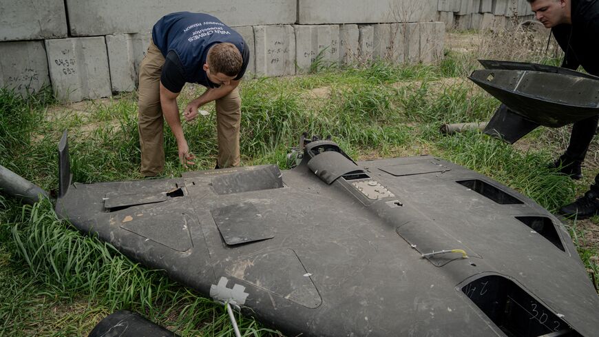 Dmytro Chubenko, spokesperson of the Kharkiv prosecutor, and his assistant look at a Russian Shahed drone shot down by Ukraine's air defense forces in a field used for the storage of Russian missiles in Kharkiv, on April 30, 2025.