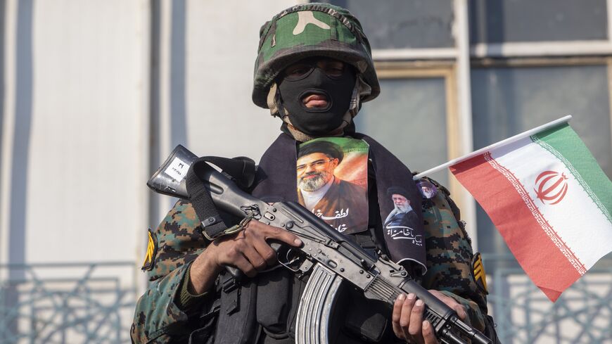 A security forces member with a picture of Iran's new supreme leader, Ayatollah Mojtaba Khamenei, watches over demonstrators as they gather for a rally in support of the new supreme leader at Enghelab Square on March 9, 2026 in Tehran, Iran. 