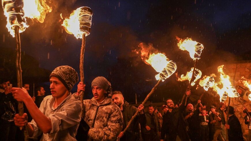 Iraqi Kurds march with torches during a procession to celebrate in the town of Akre