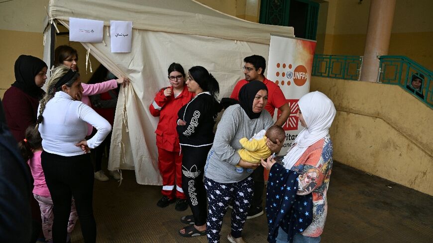 Mariam Zein (R) brings her son to a mobile health clinic run by charity Caritas Lebanon