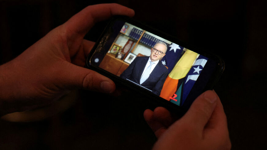 FILE PHOTO: A pub-goer watches Australian Prime Minister Anthony Albanese deliver his address to the nation over the Iran crisis, on his phone at a pub in Sydney, Australia, April 1, 2026. REUTERS/Hollie Adams/File Photo