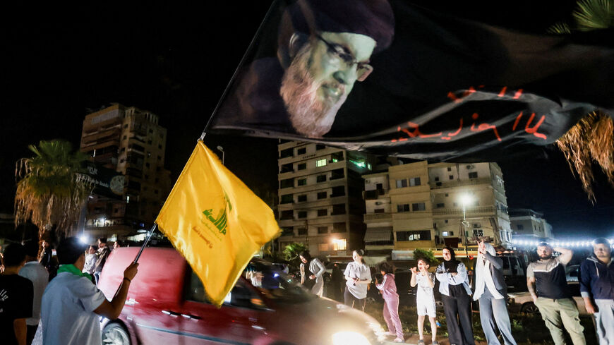 A man holds a large flag with an image depicting former Hezbollah leader Hassan Nasrallah, as displaced people return to their homes after a 10-day ceasefire between Lebanon and Israel went into effect, in Sidon, Lebanon, April 17, 2026. REUTERS/Aziz Taher
