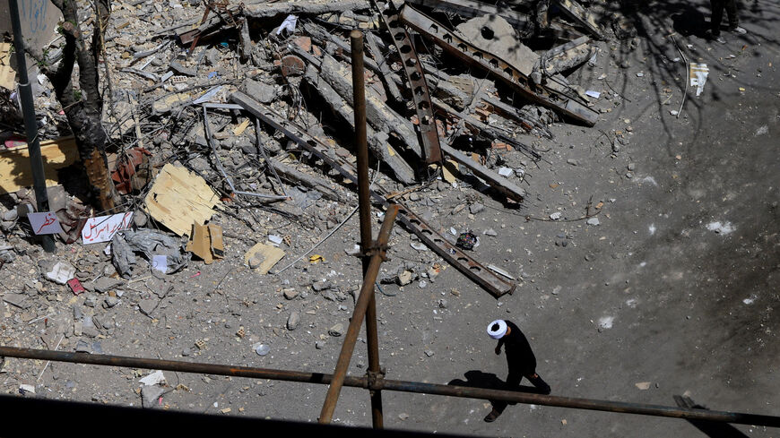 A cleric walks near a residential building damaged by a strike on March 4, in Tehran, Iran, April 14, 2026. REUTERS/Thaier Al Sudani