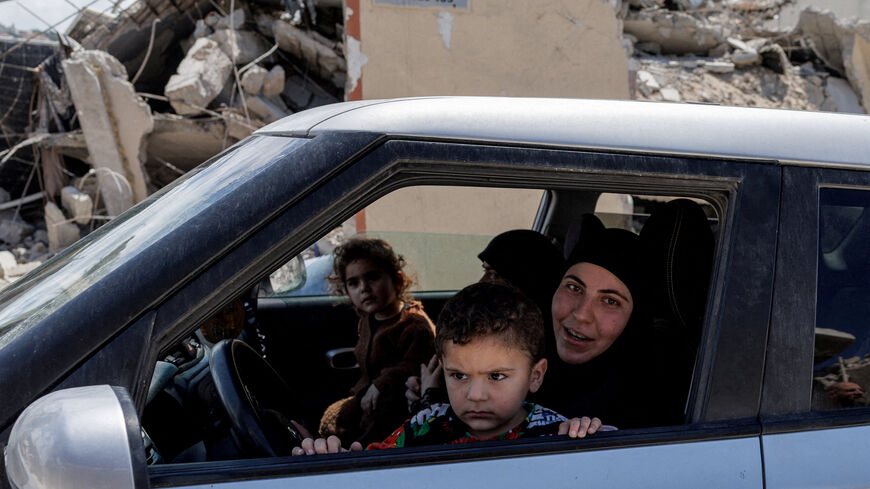 A family drives past shops and houses damaged by an Israeli strike, amid a 10-day ceasefire between Lebanon and Israel, in Mansouri village, southern Lebanon, April 21, 2026. REUTERS/Zohra Bensemra     TPX IMAGES OF THE DAY