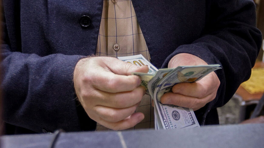 FILE PHOTO: A man counts U.S. dollars at a currency exchange shop in Baghdad, Iraq, January 23, 2023. REUTERS/Ahmed Saad/ File Photo