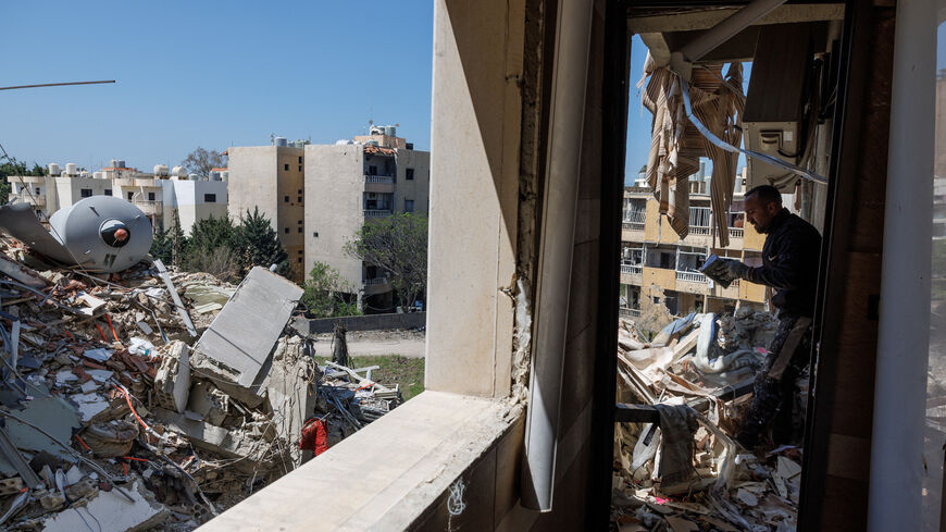 A man checks a book that was found among rubble as he cleans an apartment in a building damaged by an Israeli strike, amid a temporary ceasefire between Lebanon and Israel, in Tyre, April 23, 2026. REUTERS/Zohra Bensemra