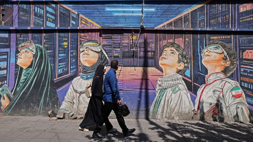 People walk past a wall mural along the roadside in Tehran on April 12, 2026.