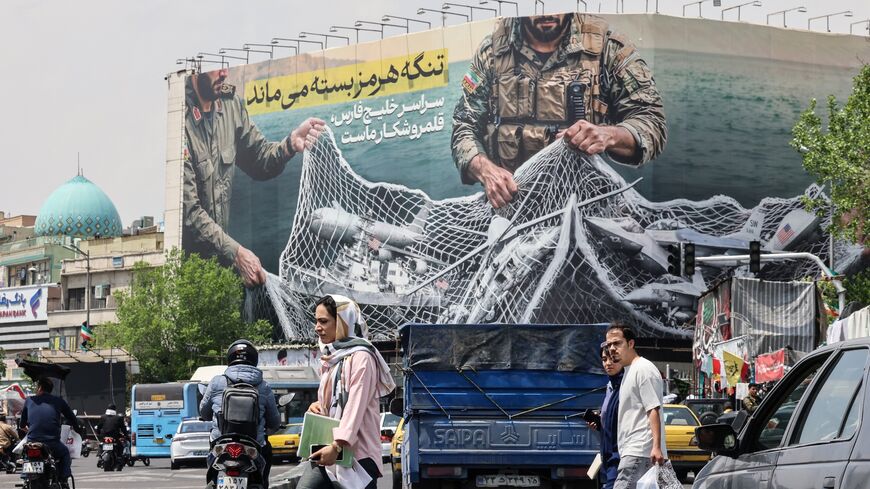 Iranian walks past a giant billboard reading "The Strait of Hormuz remains closed" at the Revolution Square in Tehran on April 22, 2026.