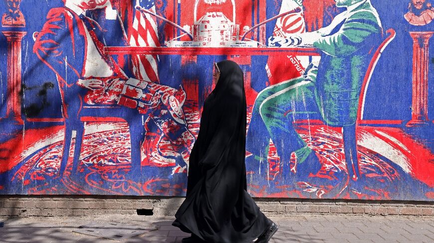 A woman walks past an anti-US mural depicting Iran-US talks near the former US embassy in Tehran 