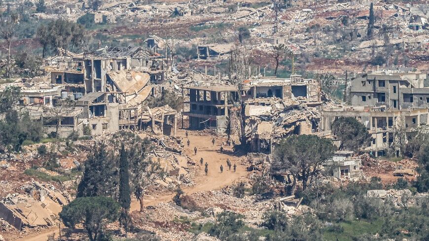 Israeli soldiers walking along the road between destroyed houses in southern Lebanon 