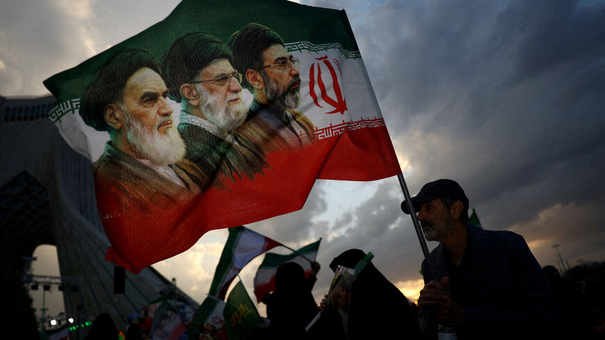 FILE PHOTO: A man holds a flag with a picture of late leader of the Islamic Revolution Ayatollah Ruhollah Khomeini, late Supreme Leader of Iran Ayatollah Ali Khamenei and Iran's new Supreme Leader Mojtaba Khamenei, during a rally in Tehran, Iran, April 29, 2026. Majid Asgaripour/WANA (West Asia News Agency) via REUTERS/File Photo
