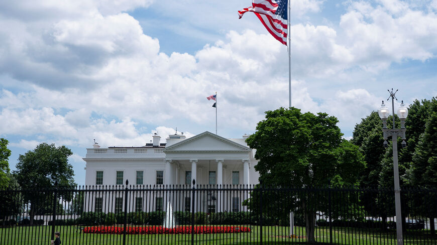 A visitor walks past the White House and a new flag pole installed on the North Lawn in Washington, D.C., U.S., June 19, 2025. REUTERS/Nathan Howard