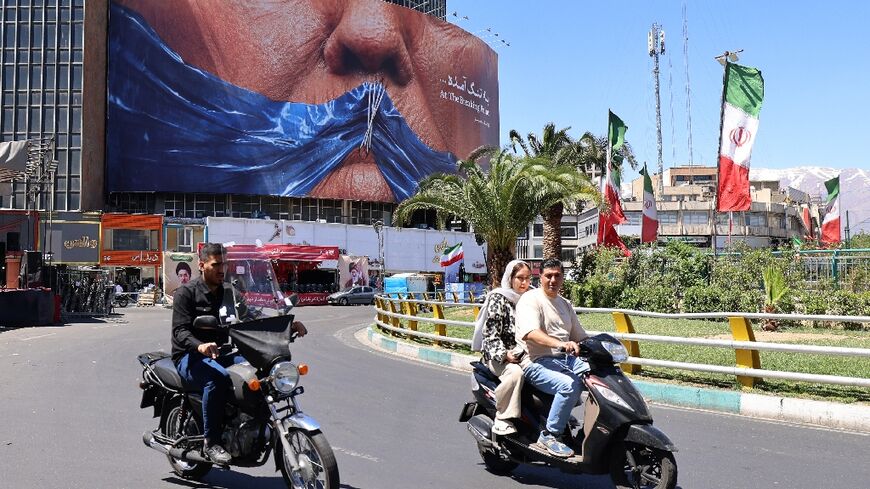 Commuters in Tehran drive past a billboard mocking US President Donald Trump over the Strait of Hormuz