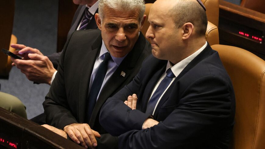 Israeli Minister of Foreign Affairs Yair Lapid (L) speaks to outgoing Prime Minister Naftali Bennett, during a meeting at the Knesset (parliament), in Jerusalem on June 30, 2022. - Final approval of the parliament dissolution bill was initially expected by midnight but was postponed to June 30 as coalition and opposition lawmakers sparred over last-minute legislative details, several sources familiar with the parliamentary said. (Photo by Menahem KAHANA / AFP) (Photo by MENAHEM KAHANA/AFP via Getty Images)