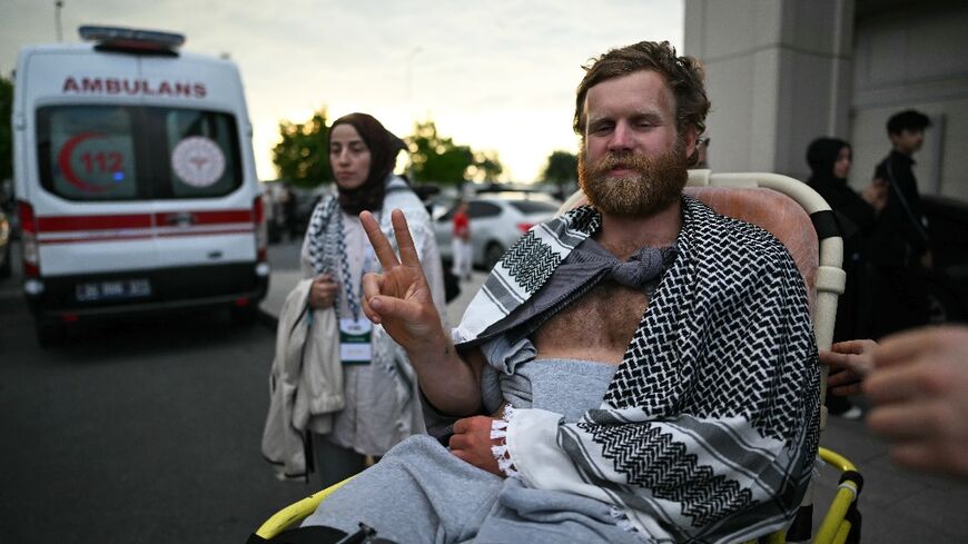 A member of the Global Sumud Flotilla arrested and deported by Israel gives the V-sign as he is brought out of a terminal at Istanbul Airport 