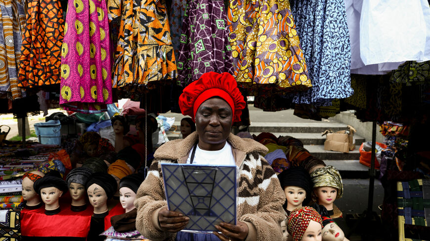 A woman tries on a new hat in the 800 metre-long Tuesday Market in Sarcelles, which has vendors selling food, clothing, homeware products and handicrafts to cater for Sarcelles' diverse immigrant community in the Paris suburb of Sarcelles, France, April 14, 2026. REUTERS/Tom Nicholson