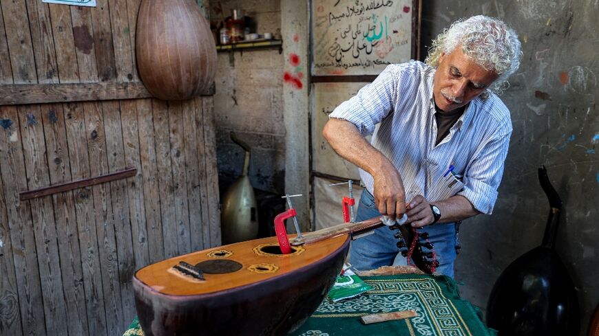 Displaced Palestinian craftsman Suhail Abu Shawish repairing damaged Ouds inside a workship in Gaza's Nuseirat refugee camp