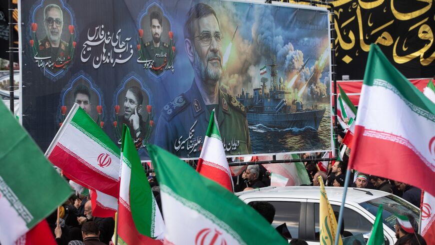 Members of the crowd wave Iranian flags during a funeral procession held for IRGC Navy Chief Alireza Tangsiri.