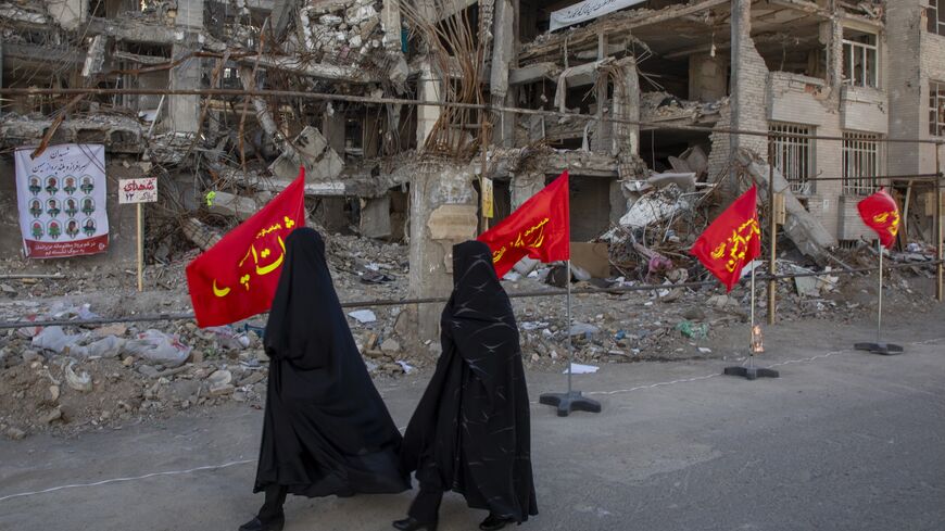 Women walk past buildings destroyed in a joint attack by Israel and the United States on April 6, 2026, in Tehran, Iran. 