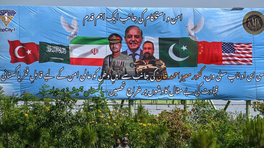 Motorcyclists ride past a billboard featuring Pakistan's Prime Minister Shehbaz Sharif (C) and Army Chief and Field Marshal Syed Asim Munir (L) in Islamabad on April 20, 2026, ahead of anticipated US-Iran peace talks. 