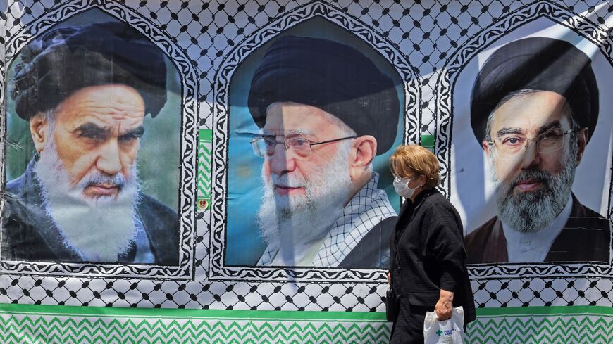 A woman walks past a banner bearing the images of the late founder of the Islamic Revolution supreme leader Ayatollah Ruhollah Khomeini (L).
