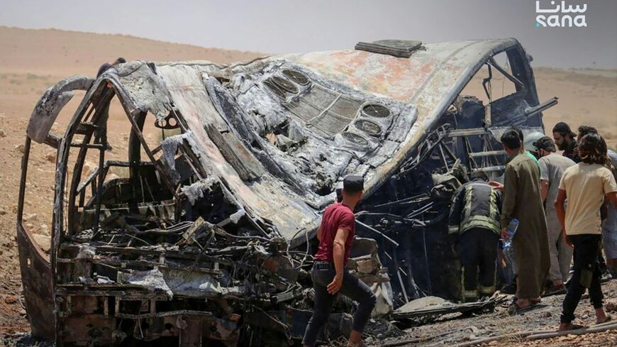 This handout picture taken and released by the official Syrian Arab News Agency (SANA) on July 25, 2026 shows people and first responders inspecting the damage at the scene of the collision of two passenger buses on the Damascus-Deir Ezzor road
