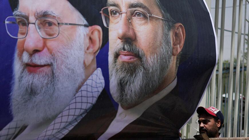 A man mounts a banner depicting Iran's late Supreme Leader Ayatollah Ali Khamenei and Iran's Supreme Leader Ayatollah Mojtaba Khamenei, onto a fence during preparations for a farewell ceremony for Iran's late Supreme Leader Ayatollah Ali Khamenei who was killed on February 28 in Israeli and U.S. airstrikes, otside the Imam Khomeini Grand Mosalla, in Tehran, Iran July 2, 2026. REUTERS/Mohammed Salem