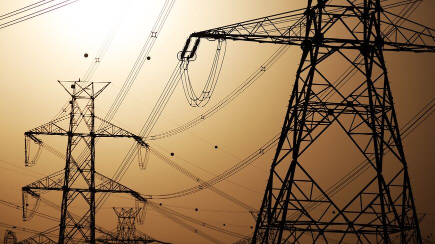 The sun sets behind overhead power lines in Kuwait City, June 19, 2024.