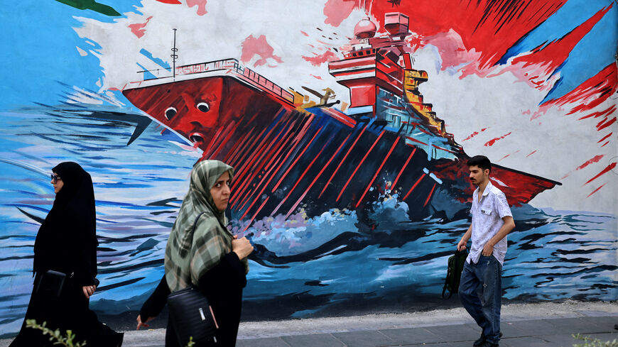 Commuters walk past a wall mural along the street in Tehran on July 21, 2026. Iran's Revolutionary Guards said on July 21 they hit US military targets including air defence systems in Bahrain and Kuwait, state news agency IRNA reported. (Photo by ATTA KENARE / AFP via Getty Images) /
