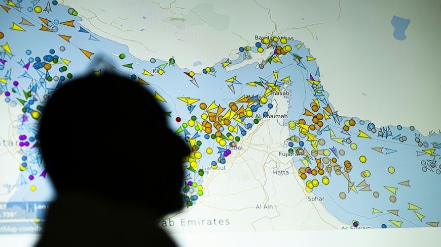 A person in front of a large screen displaying vessel movements in the Strait of Hormuz on a ship-tracking website