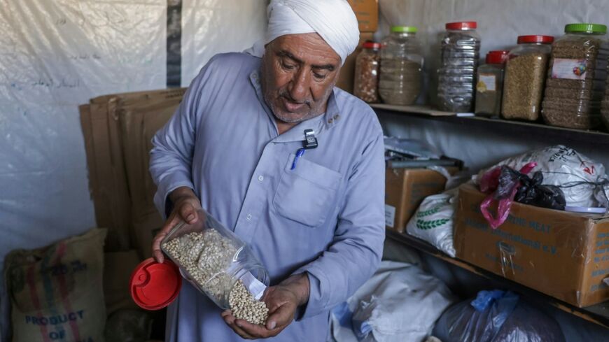 Salem Muhanna, who manages the Al Qarara Seed Bank with support from the ICRC, displays white cowpea seeds at the bank, in Deir el-Balah, central Gaza Strip