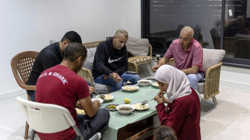 US-Palestinian dual citizen Louai Abu Ridi (C), whose home in the occupied West Bank village of Qusra is besieged by Israeli settlers, shares an evening meal with family members at the home in Qusra