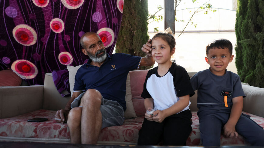 Marmar Ouda sits with his grandchildren in his home in the Palestinian village Qusra in the Israeli-occupied West Bank  August 14, 2026. REUTERS/Ammar Awad
