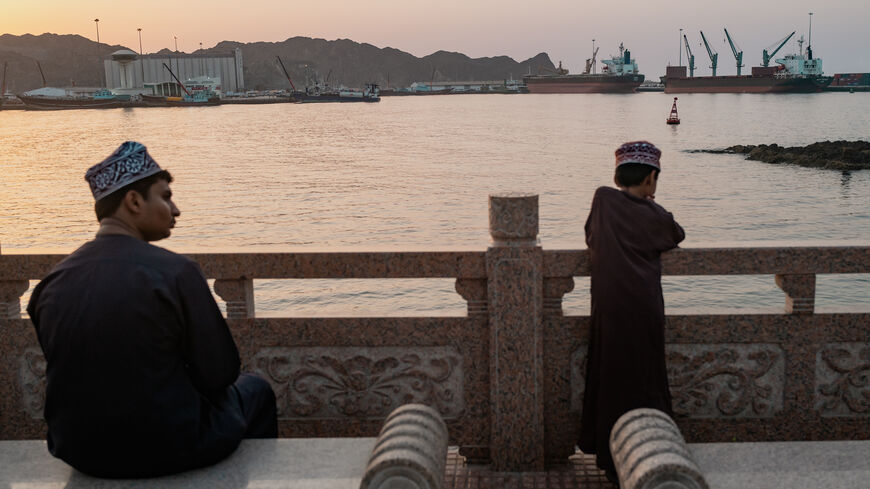 Two brothers watch oil tankers, general cargo ships, bulk carriers, and fishing boats anchored in the waters off Muscat near the Strait of Hormuz on June 18, 2026 in Muscat, Oman.