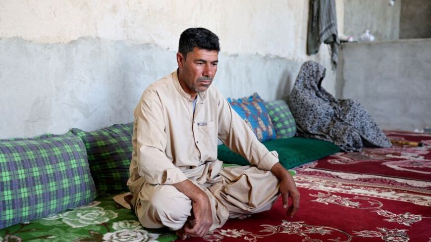 Abdul Jabbar sits next to his mother at their house in Farah province