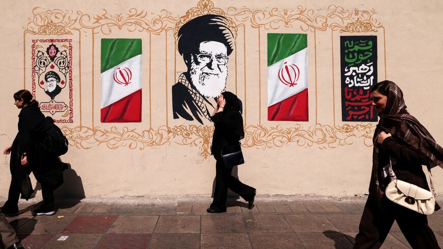Iranians walk past a wall decorated with the image of assassinated Iranian supreme leader Ayatollah Ali Khamenei and the national flag, in central of Tehran on Sept. 14, 2026.  