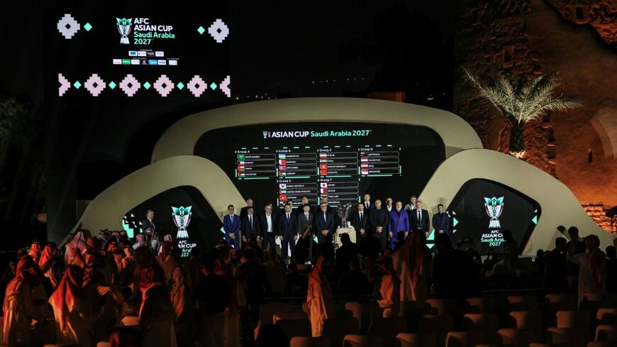 Coaches of Asian national football teams pose in front of a screen showing the results of the draw last year