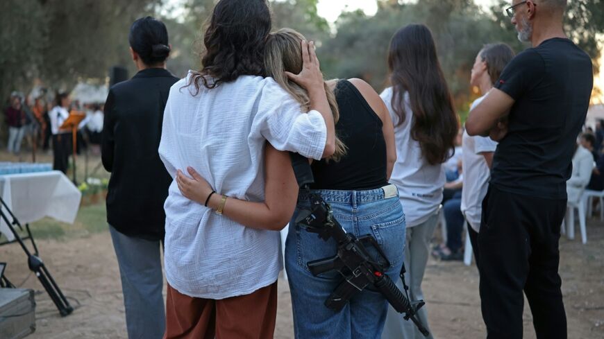 Israelis embrace one another while attending an October 7 attack three-year-anniversary tribute ceremony at the Kibbutz Kfar Aza