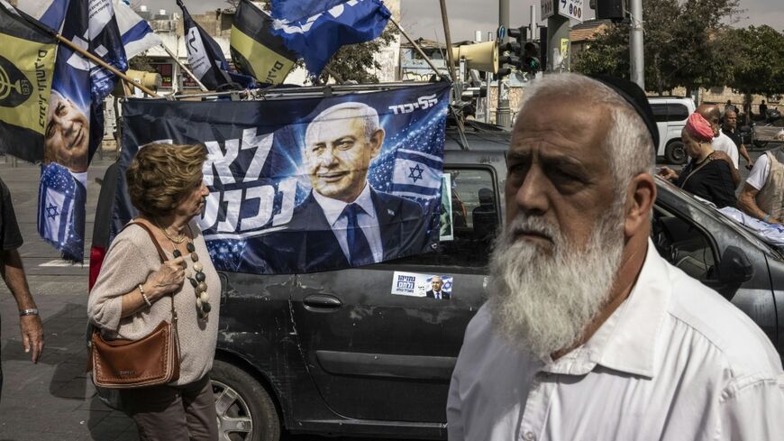 People walk past election campaign flags and a car plastered with images of Israeli Prime Minister Benjamin Netanyahu in Jerusalem on October 16, 2026